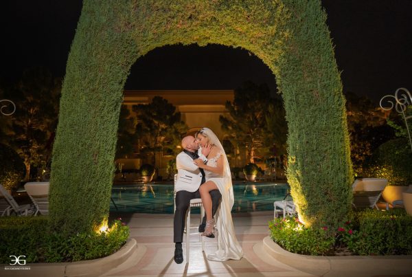 Bride and Groom in All White Kissing Under Arch Las Vegas