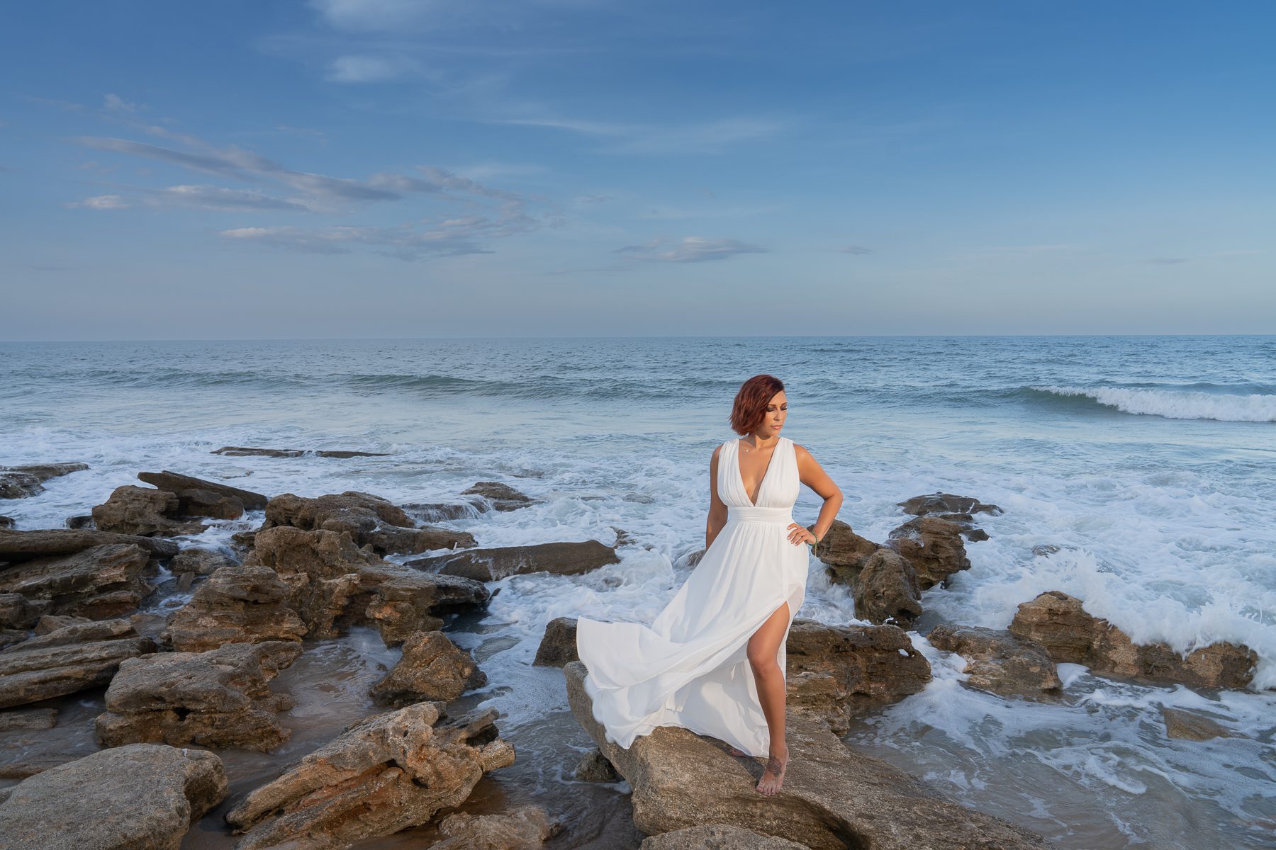 Woman in white dress on stones seaside