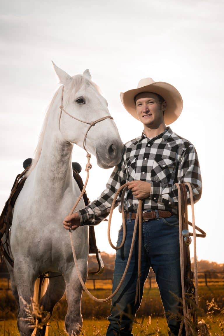 Horse trainer in a cowboy hat standing beside a white horse in Kentucky
